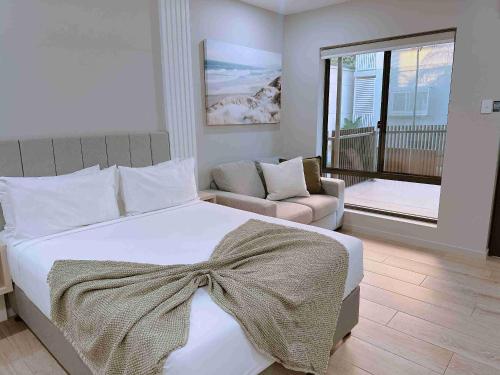 a bedroom with a bed and a couch and a window at Belmoral Corporate Suites in Townsville