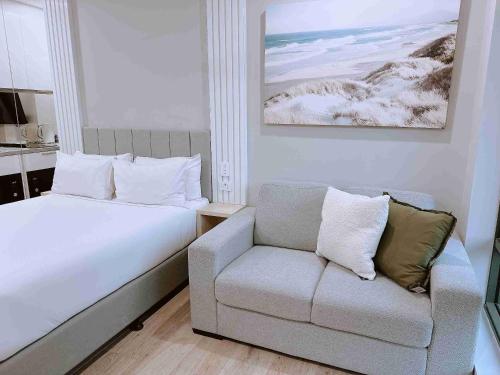 a bedroom with a bed and a couch and a chair at Belmoral Corporate Suites in Townsville