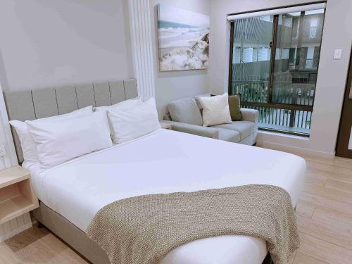 a bedroom with a large white bed and a couch at Belmoral Corporate Suites in Townsville