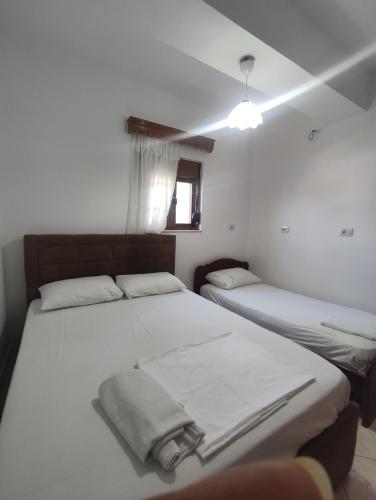 a bedroom with two beds with white sheets and a window at Galia Apartment in Ksamil