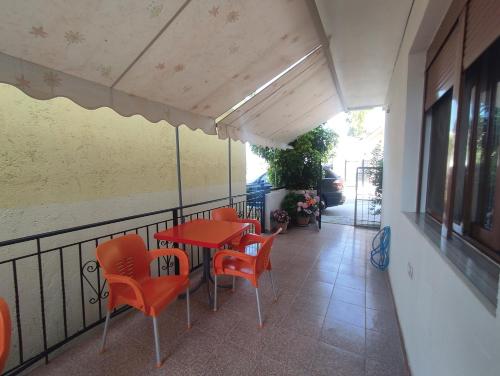 a patio with a red table and chairs on a balcony at Galia Apartment in Ksamil
