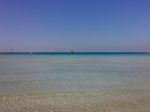 a large body of water with a red boat in the distance at Dimora Il Girasole in Torre San Giovanni Ugento