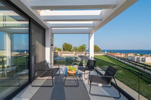 a patio with chairs and a table on a balcony at Villa Amelia by Travel Pro - Mouries Halkidiki in Paralia Dionysiou
