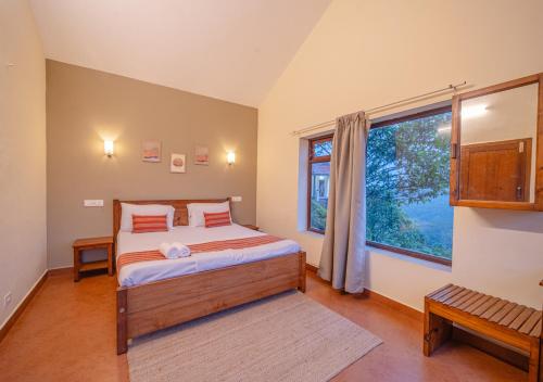 a bedroom with a bed and a large window at Aruvi Mountain Villa Vagamon by VOYE HOMES in Vagamon