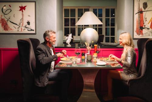 a man and woman sitting at a table in a restaurant at Cortisen am See - Adults only in St. Wolfgang