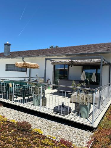 a house with a deck with an umbrella and chairs at Moderne Ferienwohnung Nähe Bad Griesbach, Haarbach in Haarbach