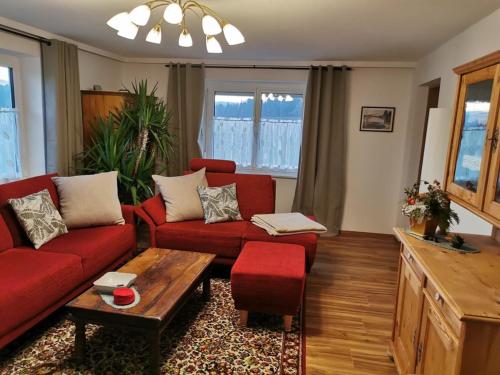 a living room with a red couch and a table at Böhmerwald fun in Schwarzenberg am Bohmerwald