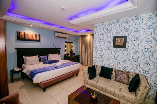 a bedroom with a king sized bed and a couch at Elegance Suites Hotels in Lagos