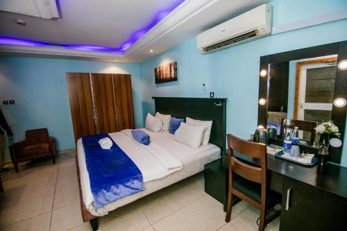 a bedroom with a bed and a desk with a desk at Elegance Suites Hotels in Lagos