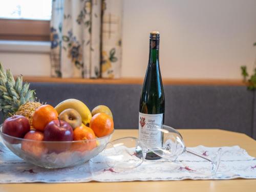 a bottle of wine and a bowl of fruit on a table at Apartment in Wald near Krimml Waterfalls in Wald im Pinzgau