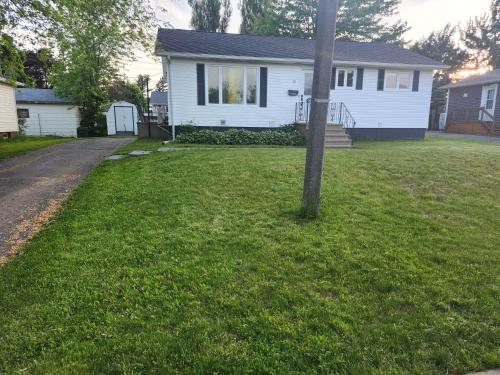 a white house with a pole in the grass at Cozy Sim's in Moncton