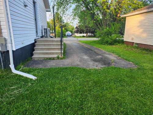 a driveway next to a house with a grass yard at Cozy Sim's in Moncton
