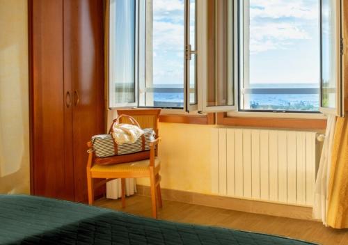 a bedroom with a chair and windows with the ocean at Hotel & Residence Venezia 2000 in Venice-Lido