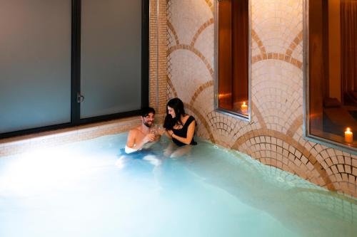 a man and a woman sitting in a swimming pool at Grand Hotel Forlì in Forlì