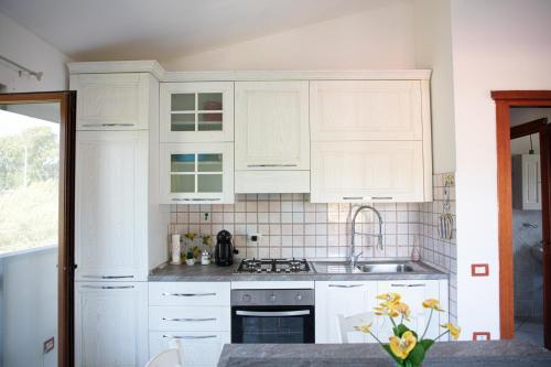 a kitchen with white cabinets and a sink at BIG RIVER HOUSE, Fronte Temo in Bosa Marina