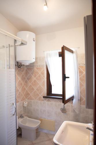 a bathroom with a sink and a toilet and a window at BIG RIVER HOUSE, Fronte Temo in Bosa Marina