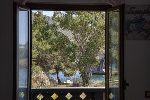 a window with a view of a tree and water at BIG RIVER HOUSE, Fronte Temo in Bosa Marina