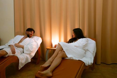 a man and a woman sitting in towels on beds at Grand Hotel Forlì in Forlì
