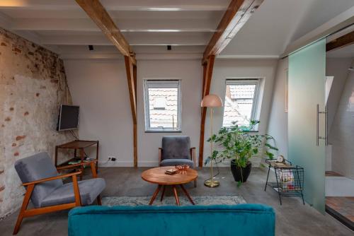 a living room with a blue couch and a table at Elburg-Vesting sfeervol appartement Bij de jufferen in Elburg