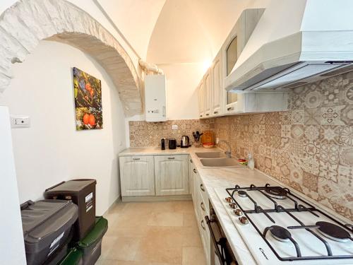 una cucina con mobili bianchi e un forno a piano cottura di Il Cuore del Borgo - Terrace In The Old Town a Locorotondo