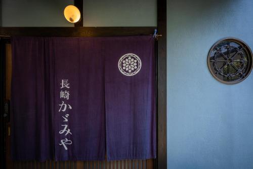 a purple curtain with writing on it next to a wall at Nagasaki Kagamiya in Nagasaki