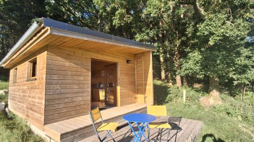 a small wooden cabin with a blue table and chairs at La ferme de beau soleil Gîte et cabanes in Saint-Gilles-du-Mené