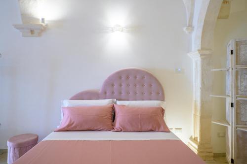 a bed with a pink headboard and pink pillows at Relais I Quattro Cuori in Martina Franca