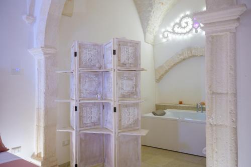 a white bathroom with a tub and a shelf at Relais I Quattro Cuori in Martina Franca