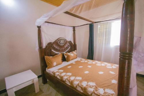 a bedroom with a four poster bed with a canopy at Havillah Gardens Watamu in Watamu