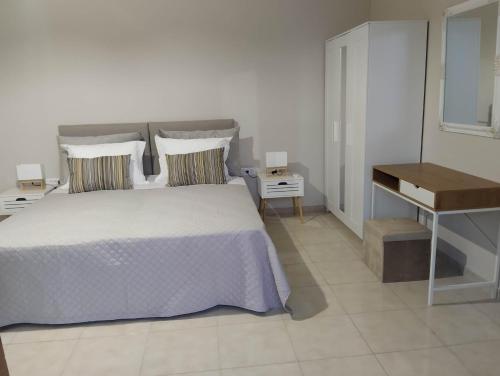 a white bedroom with a bed and a desk at Flora Beach House in Kremasti