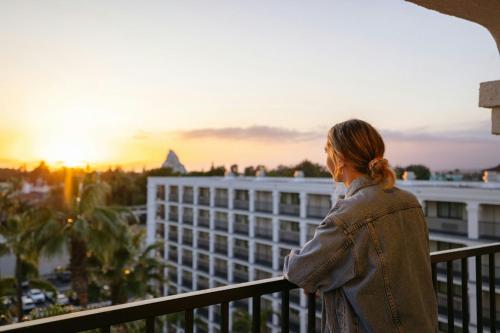 a woman standing on a balcony looking out at the sunset at Fairfield by Marriott Anaheim Resort in Anaheim