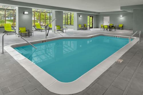 a pool in a hotel room with chairs and tables at SpringHill Suites Detroit Auburn Hills in Auburn Hills