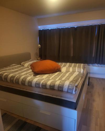 a bed with an orange pillow on top of it at Leilighet til leie på Synnfjellet in Lii