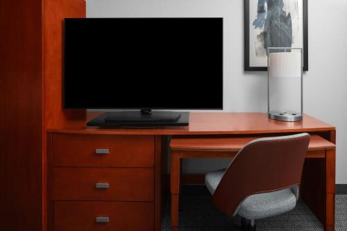 a desk with a television and a chair in a room at Courtyard by Marriott Santa Clarita Valencia in Valencia