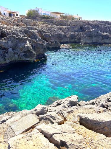 a body of water with rocks and blue water at BINIPARADISE Villas in Binibeca