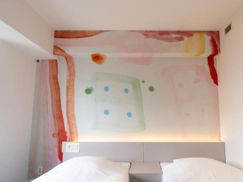 a bedroom with a wall with a painting on it at Hotel Art Stay Naha Kokusai-Dori in Naha