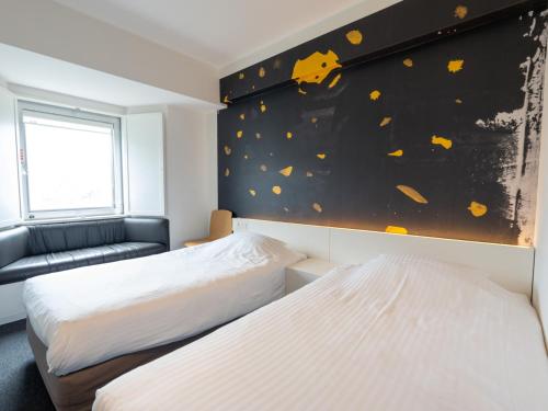 two beds in a room with a painting on the wall at Hotel Art Stay Naha Kokusai-Dori in Naha