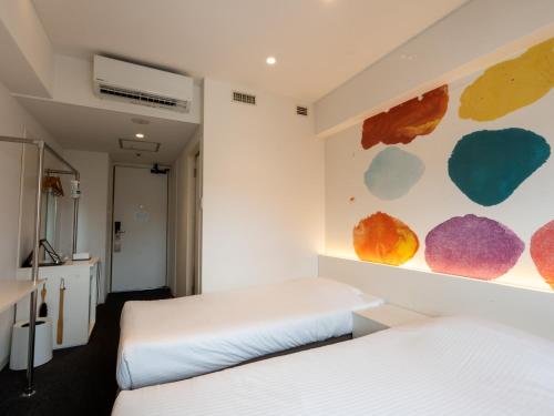 a bedroom with two beds and a painting on the wall at Hotel Art Stay Naha Kokusai-Dori in Naha