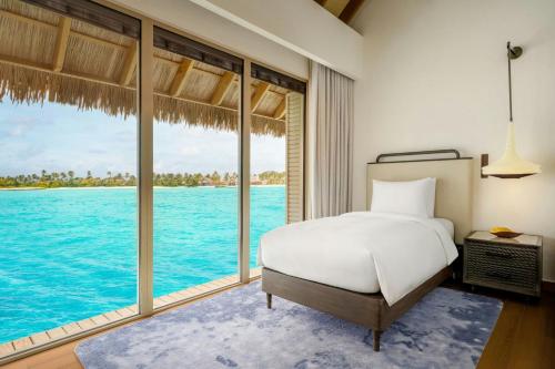 a bedroom with a bed and a view of the ocean at JW Marriott Maldives Kaafu Atoll Island Resort in Male City