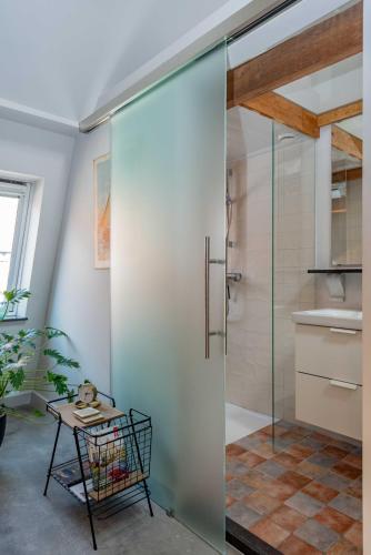 a glass shower door in a bathroom with a table at Elburg-Vesting sfeervol appartement Bij de jufferen in Elburg