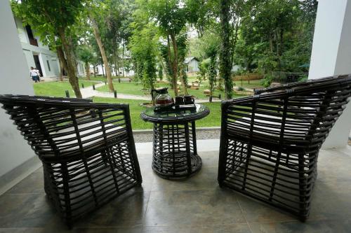 two chairs and a table on a patio with a dog at Serendib Signature Resort in Digana