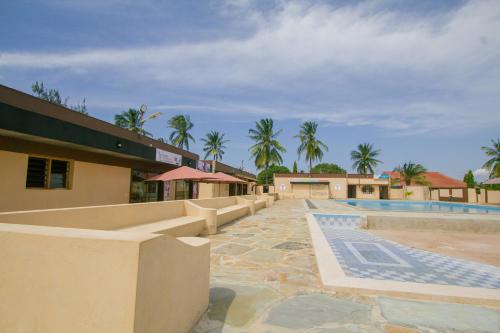 a resort with a swimming pool and palm trees at Havillah Gardens Watamu in Watamu