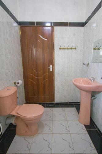 a bathroom with a pink toilet and a sink at Havillah Gardens Watamu in Watamu