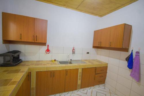 a kitchen with wooden cabinets and a sink at Havillah Gardens Watamu in Watamu
