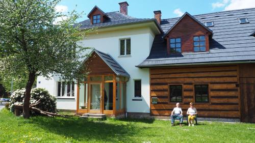 two people sitting in front of a house at Holiday House Malá Skála in Malá Skála