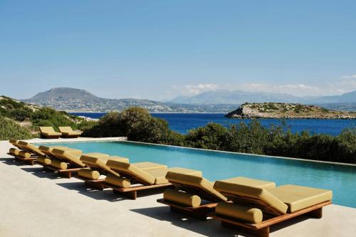 a row of lounge chairs next to a swimming pool at JW Marriott Crete Resort & Spa in Marathi