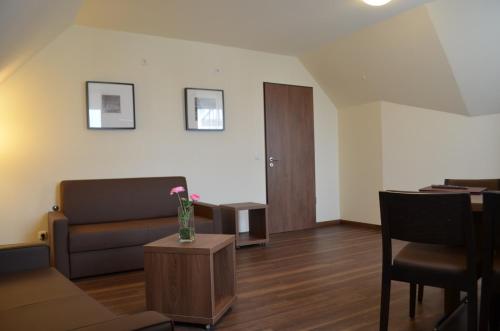 a living room with a couch and a vase of flowers on a table at Hotel Isenbütteler Hof in Isenbüttel