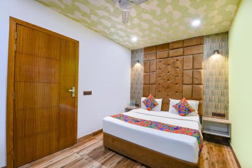 a bedroom with a bed and a wooden door at FabExpress Jeet Stays - Near Dilshad Garden Metro Station in New Delhi