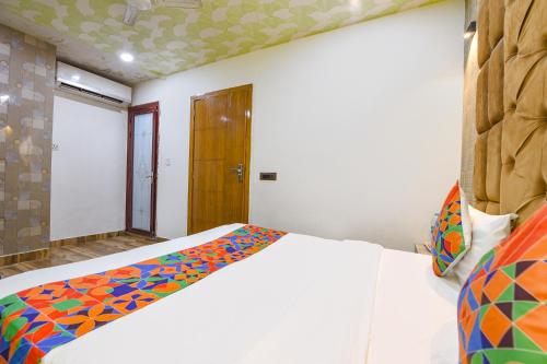a bedroom with a white bed with a colorful blanket at FabExpress Jeet Stays - Near Dilshad Garden Metro Station in New Delhi