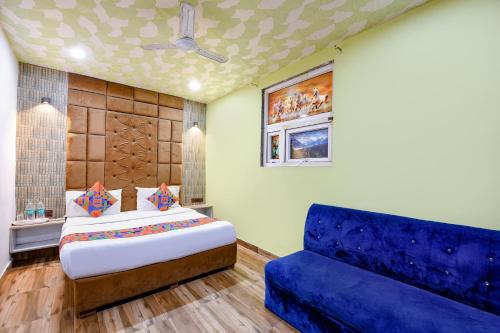 a bedroom with a bed and a blue couch at FabExpress Jeet Stays - Near Dilshad Garden Metro Station in New Delhi